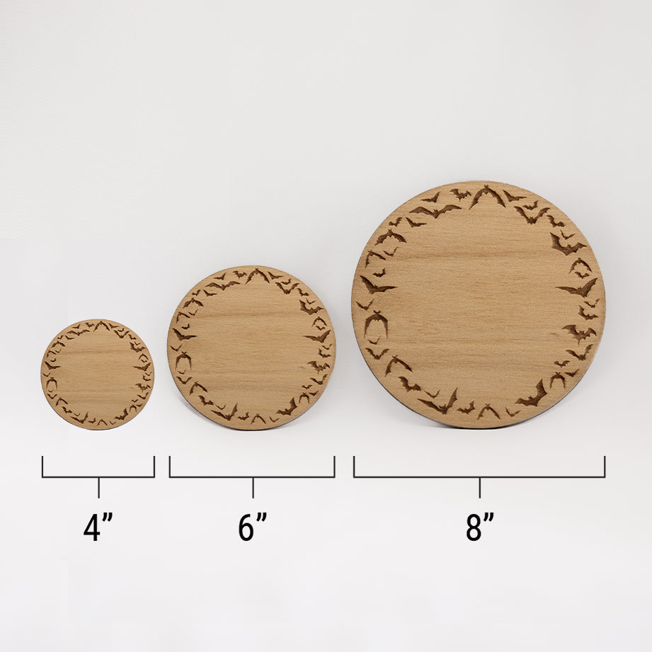 Three different sizes of the circular wooden laser-cut crystal grid engraved a border of bats in flight against a white background with a ruler underneath all three. The smallest measuring 4", the middle 6", and the largest 8".