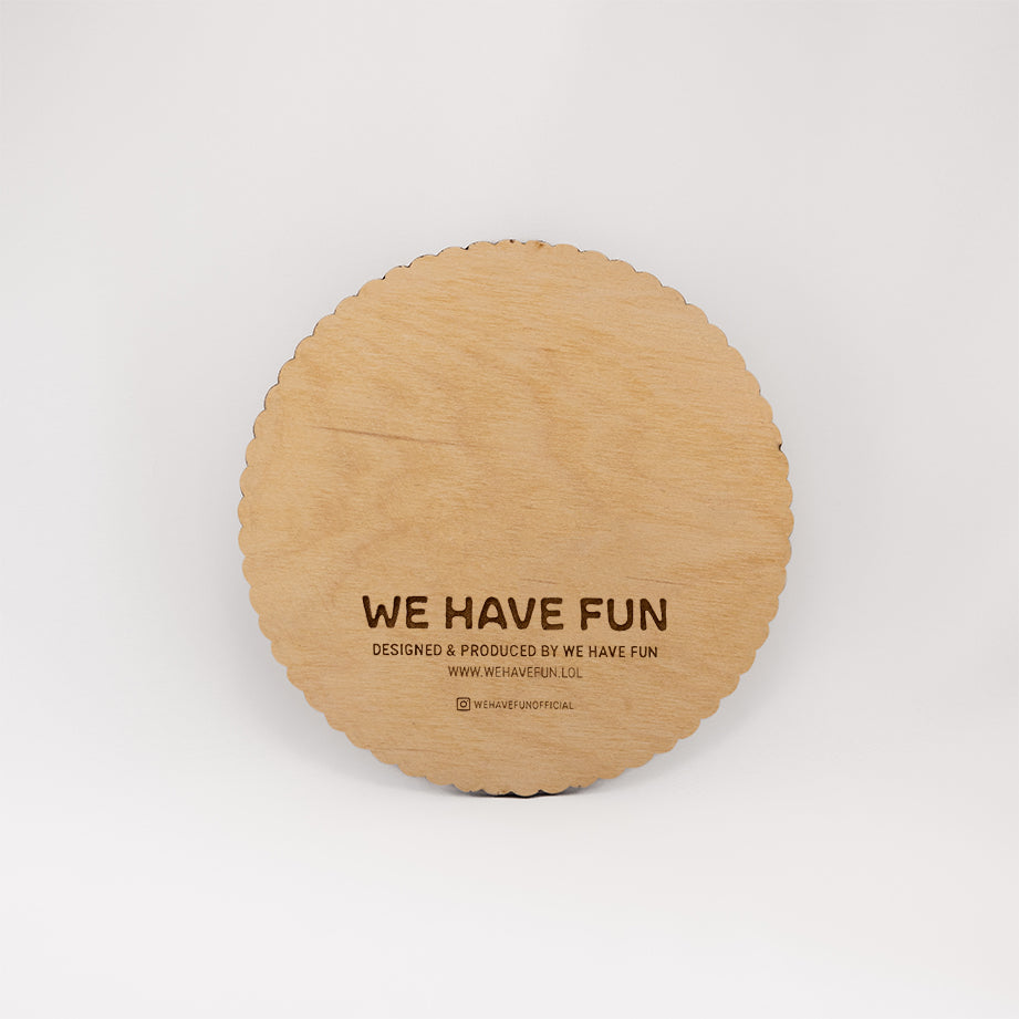 Back of the circular Baltic birch board with "We Have Fun" logo, "Designed and produced by We Have Fun", "www.wehavefun.lol", and instagram bio link "wehavefunofficial" engraved on the back. The board has a die-cut scalloped edge.