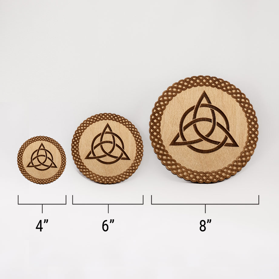 Three different sizes of the circular wooden laser-cut crystal grid engraved with the Celtic Triquetra symbol and a scalloped braid border against a white background with a ruler underneath all three. The smallest measuring 4", the middle 6", and the largest 8".