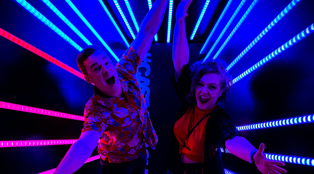 Danielle and Kris pose with arms outstretched infront of angled LED light strips