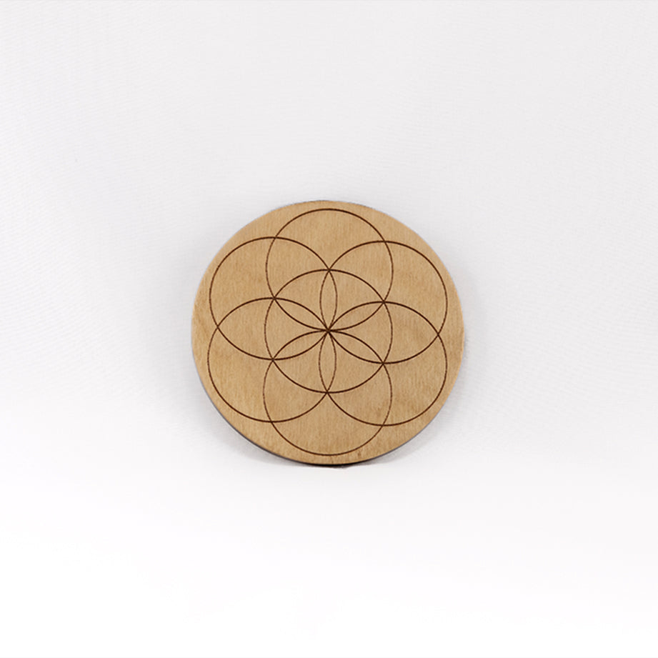 A circular wooden laser-cut crystal grid engraved with the Seed of Life with a plain white background. 