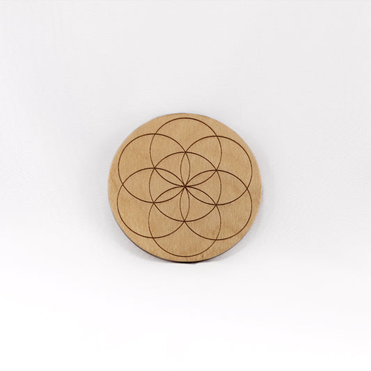 A circular wooden laser-cut crystal grid engraved with the Seed of Life with a plain white background.