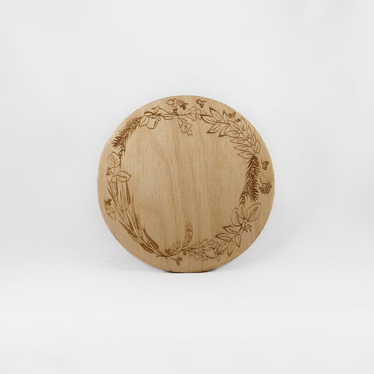 A circular wooden laser-cut crystal grid engraved with a border made up of Apple, Yew, Hazel, Edler, Elm, Willow, Oak, Alder, and Ash tree branches with a plain white background. 