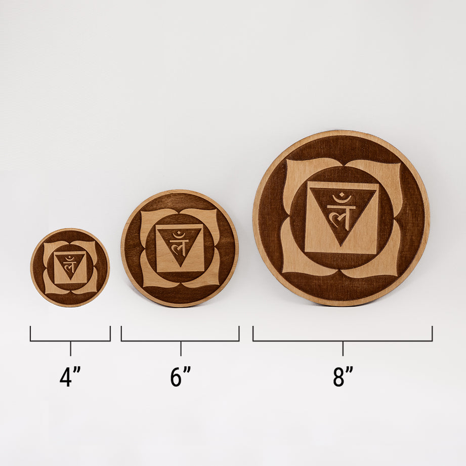 Three different sizes of the circular wooden laser-cut crystal grid engraved with the root chakra symbol against a white background with a ruler underneath all three. The smallest measuring 4", the middle 6", and the largest 8".