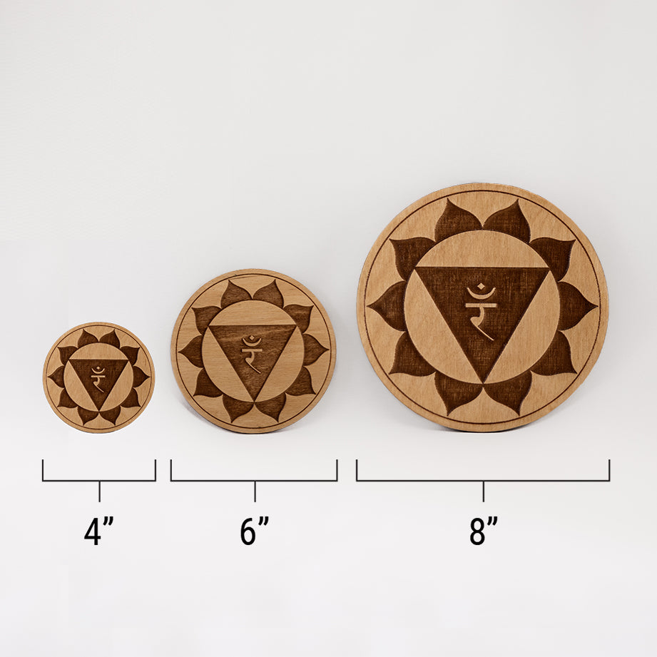 Three different sizes of the circular wooden laser-cut crystal grid engraved with the solar plexus chakra symbol against a white background with a ruler underneath all three. The smallest measuring 4", the middle 6", and the largest 8".