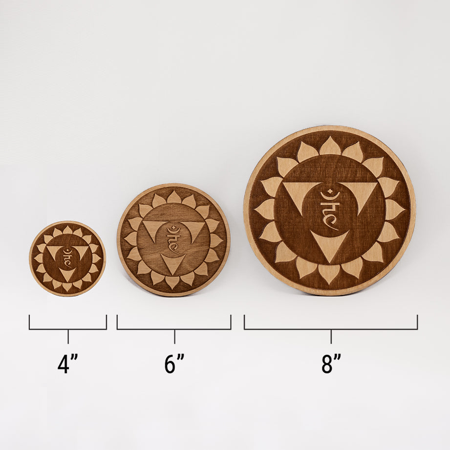 Three different sizes of the circular wooden laser-cut crystal grid engraved with the throat chakra symbol against a white background with a ruler underneath all three. The smallest measuring 4", the middle 6", and the largest 8".