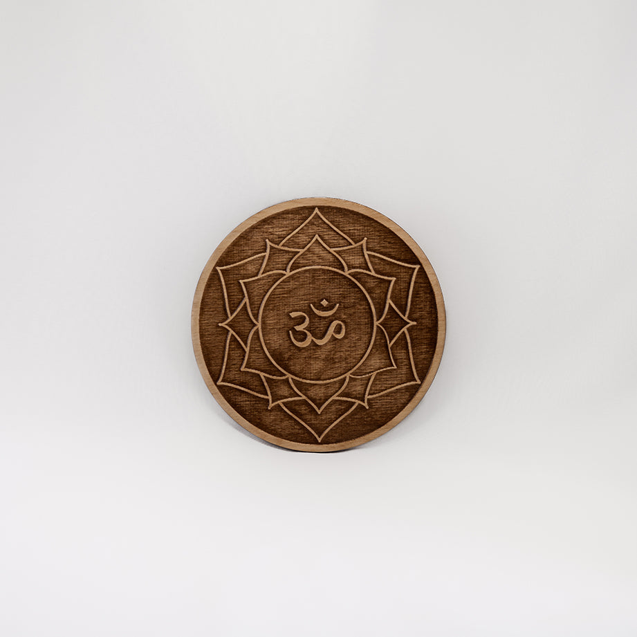 A circular wooden laser-cut crystal grid engraved with the crown chakra symbol with a plain white background. 