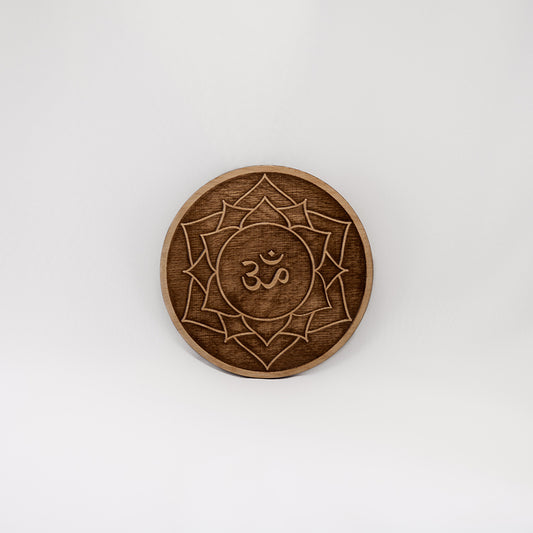 A circular wooden laser-cut crystal grid engraved with the crown chakra symbol with a plain white background.
