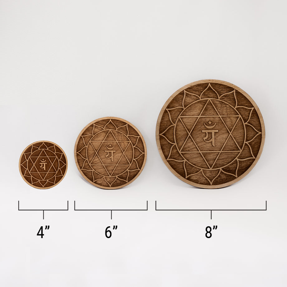 Three different sizes of the circular wooden laser-cut crystal grid engraved with the heart chakra symbol against a white background with a ruler underneath all three. The smallest measuring 4", the middle 6", and the largest 8".