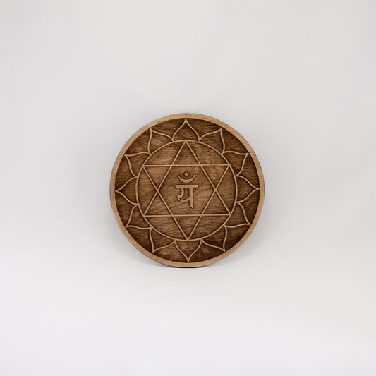 A circular wooden laser-cut crystal grid engraved with the heart chakra symbol with a plain white background. 