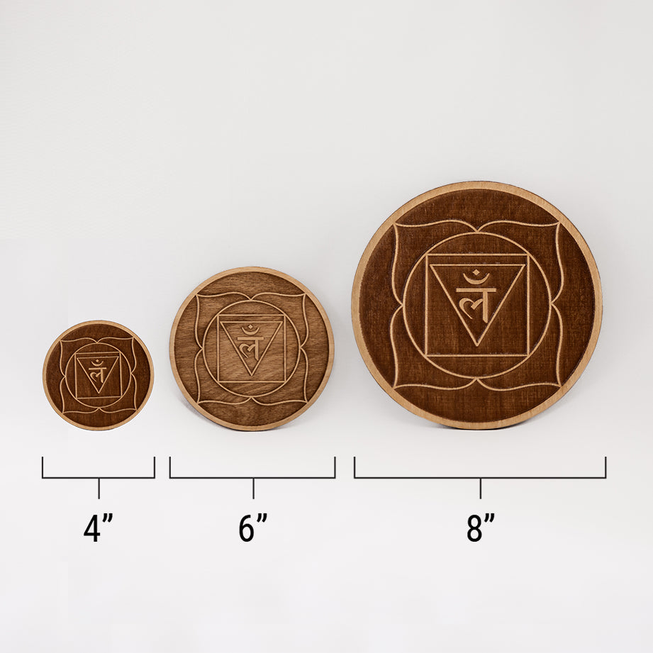 Three different sizes of the circular wooden laser-cut crystal grid engraved with the root chakra symbol against a white background with a ruler underneath all three. The smallest measuring 4", the middle 6", and the largest 8".