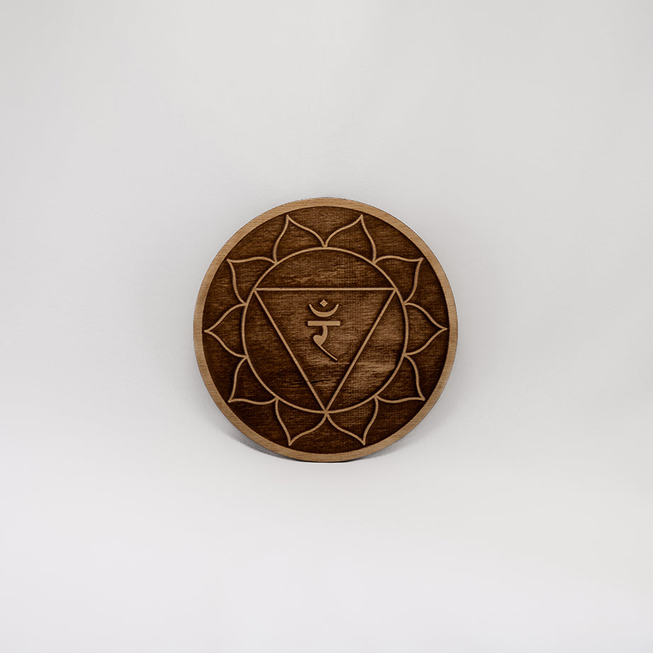 A circular wooden laser-cut crystal grid engraved with the solar plexus chakra symbol with a plain white background. 