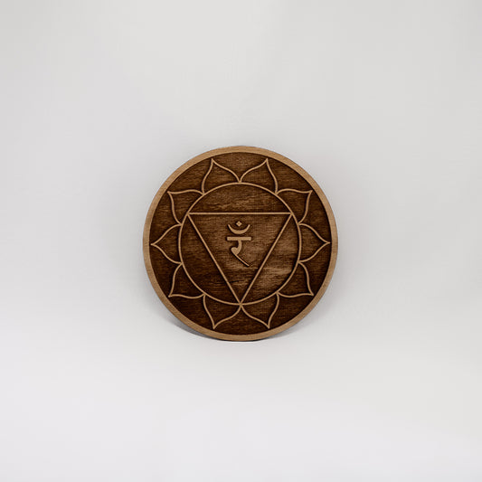 A circular wooden laser-cut crystal grid engraved with the solar plexus chakra symbol with a plain white background. 