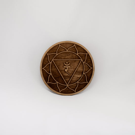 A circular wooden laser-cut crystal grid engraved with the solar plexus chakra symbol with a plain white background.