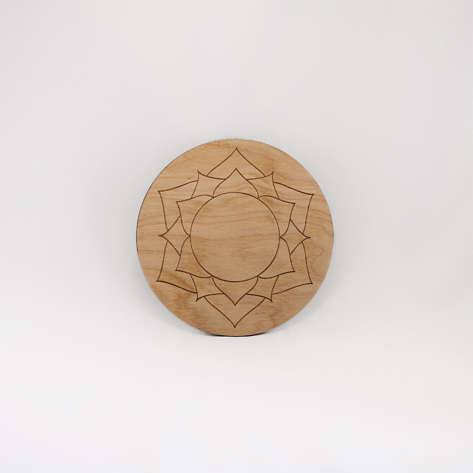 A circular wooden laser-cut crystal grid engraved with the crown chakra symbol with a plain white background. 