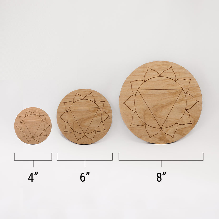 Three different sizes of the circular wooden laser-cut crystal grid engraved with the solar plexus chakra symbol against a white background with a ruler underneath all three. The smallest measuring 4", the middle 6", and the largest 8".