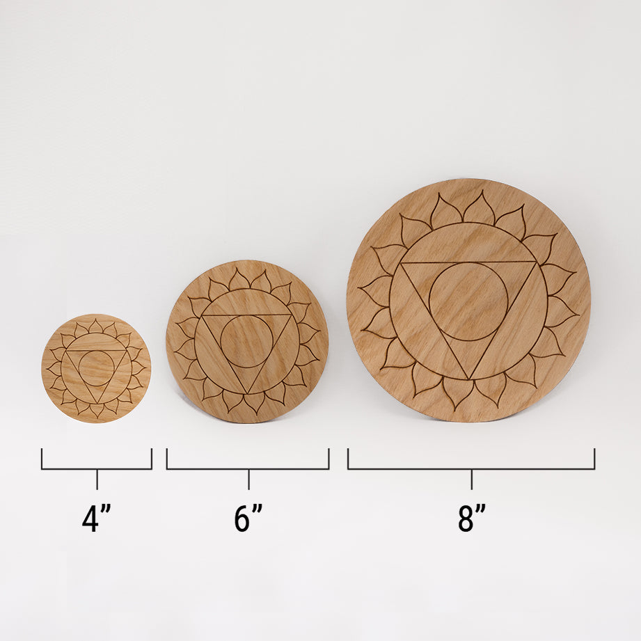 Three different sizes of the circular wooden laser-cut crystal grid engraved with the throat chakra symbol against a white background with a ruler underneath all three. The smallest measuring 4", the middle 6", and the largest 8".