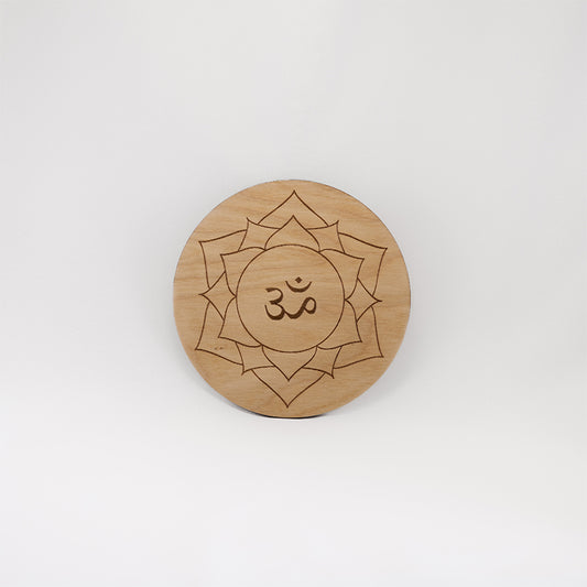A circular wooden laser-cut crystal grid engraved with the crown chakra symbol with a plain white background.
