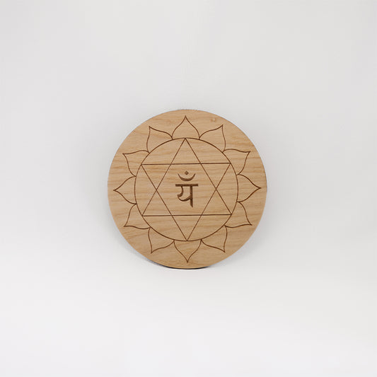 A circular wooden laser-cut crystal grid engraved with the heart chakra symbol with a plain white background.