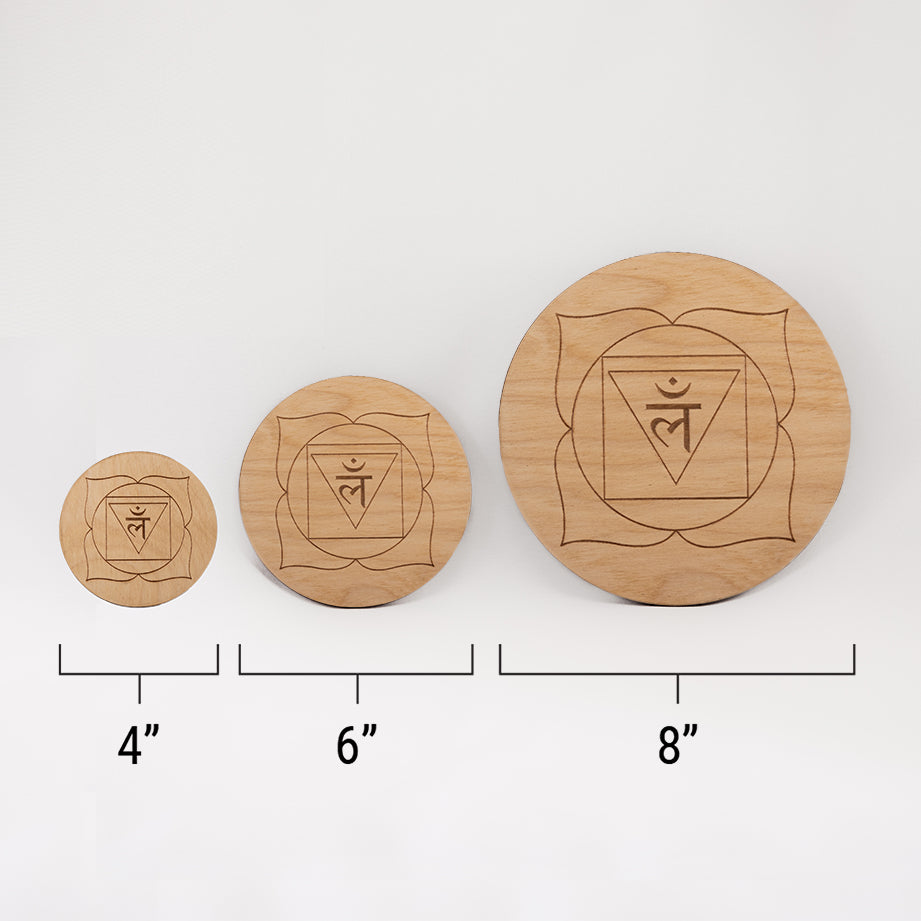 Three different sizes of the circular wooden laser-cut crystal grid engraved with the root chakra symbol against a white background with a ruler underneath all three. The smallest measuring 4", the middle 6", and the largest 8".