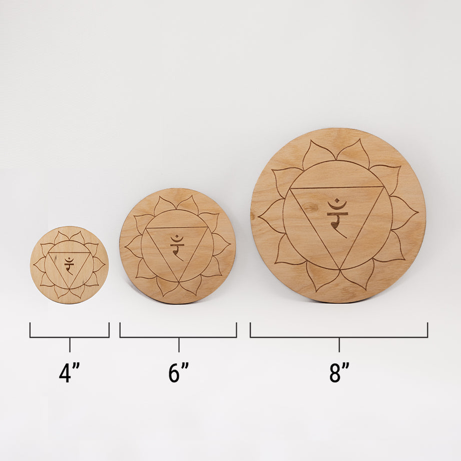 Three different sizes of the circular wooden laser-cut crystal grid engraved with the solar plexus chakra symbol against a white background with a ruler underneath all three. The smallest measuring 4", the middle 6", and the largest 8".