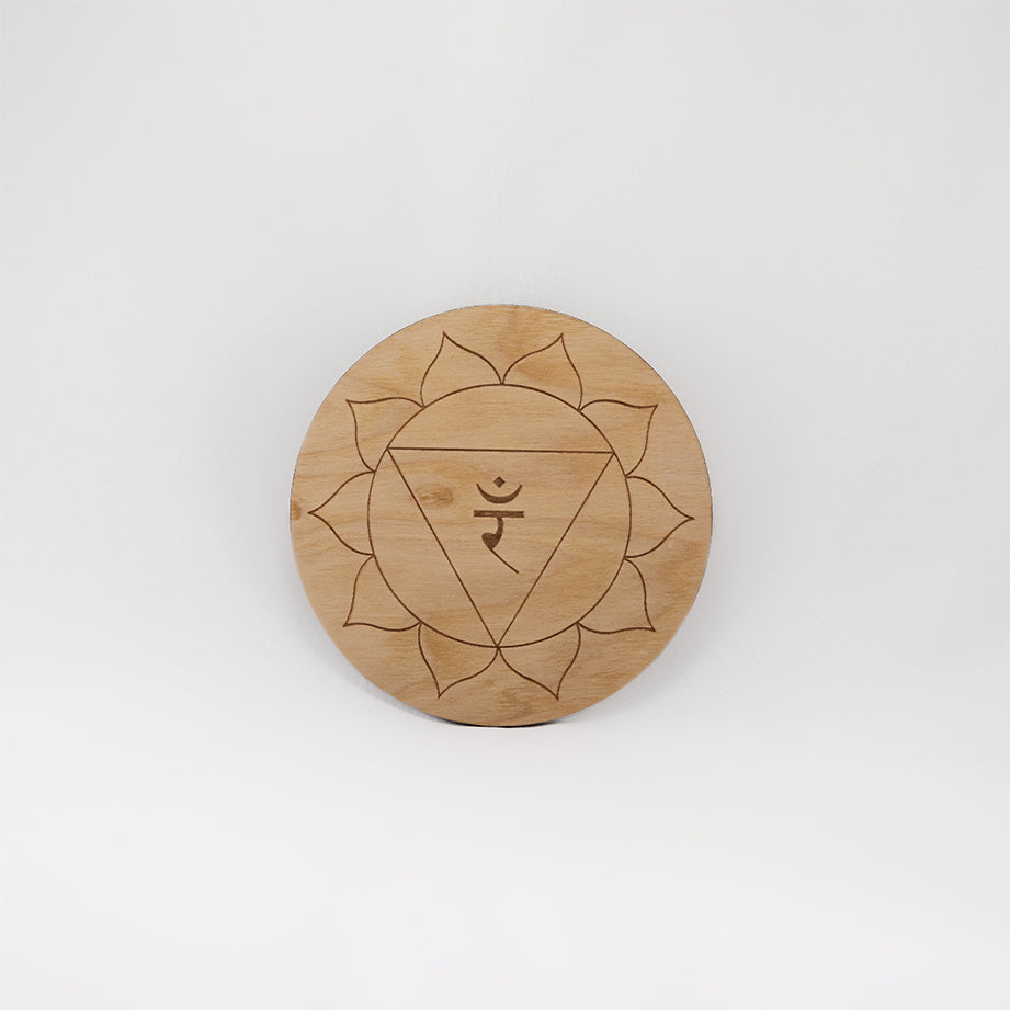 A circular wooden laser-cut crystal grid engraved with the solar plexus chakra symbol with a plain white background. 