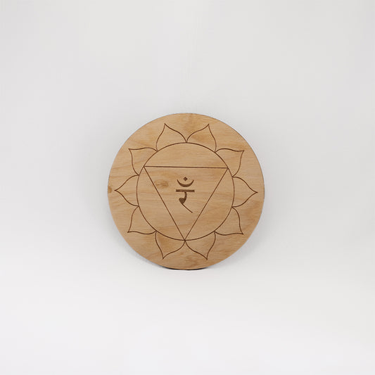 A circular wooden laser-cut crystal grid engraved with the solar plexus chakra symbol with a plain white background.