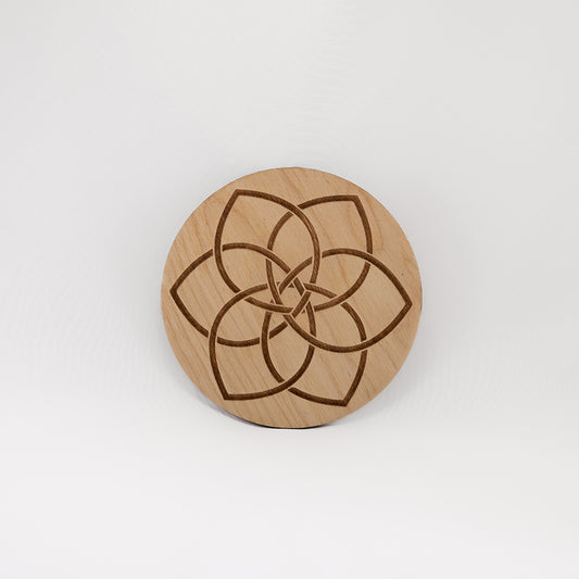 A circular wooden laser-cut crystal grid engraved with a Celtic flower knot with a plain white background. 