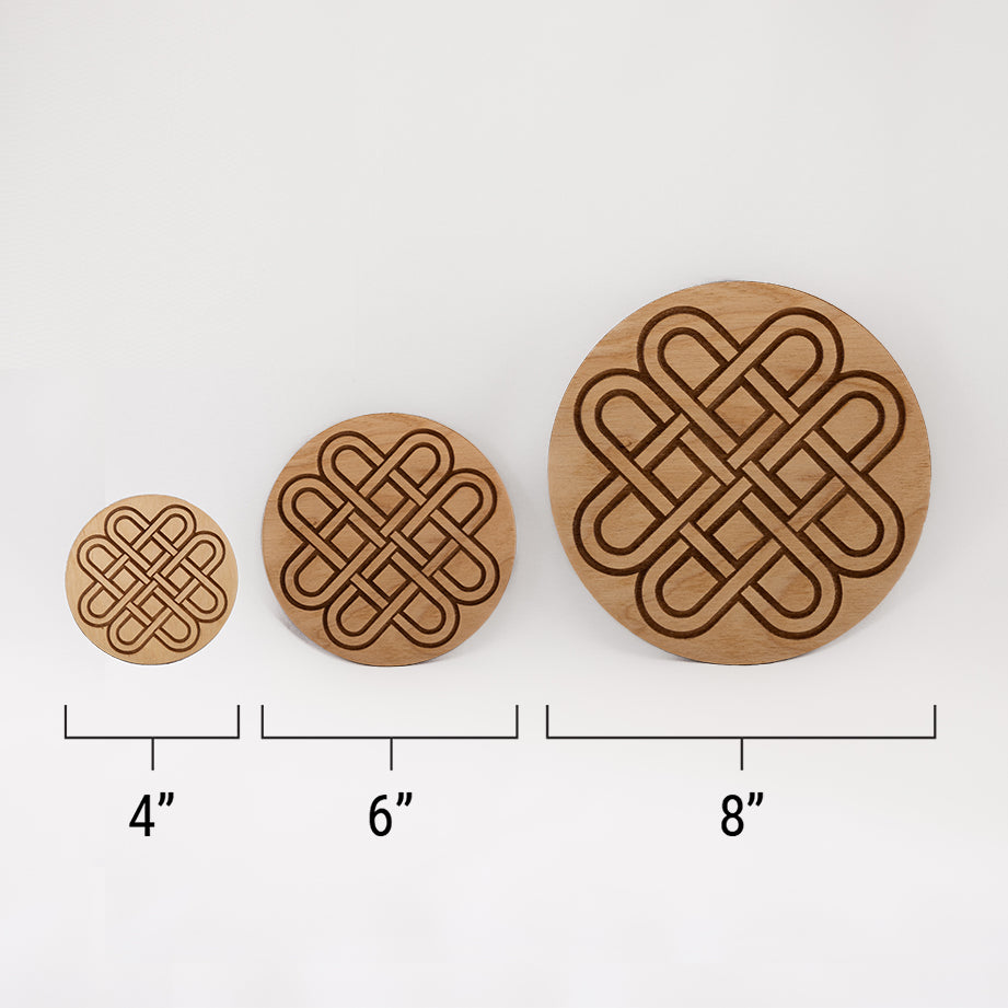 Three different sizes of the circular wooden laser-cut crystal grid engraved with a Celtic knot against a white background with a ruler underneath all three. The smallest measuring 4", the middle 6", and the largest 8".