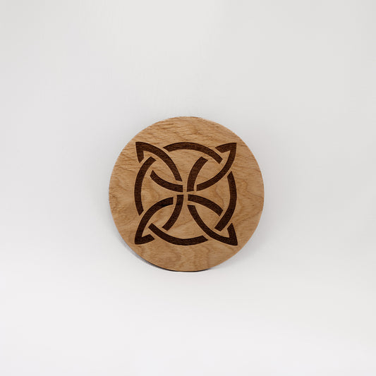 A circular wooden laser-cut crystal grid engraved with a Celtic knot with a plain white background. 