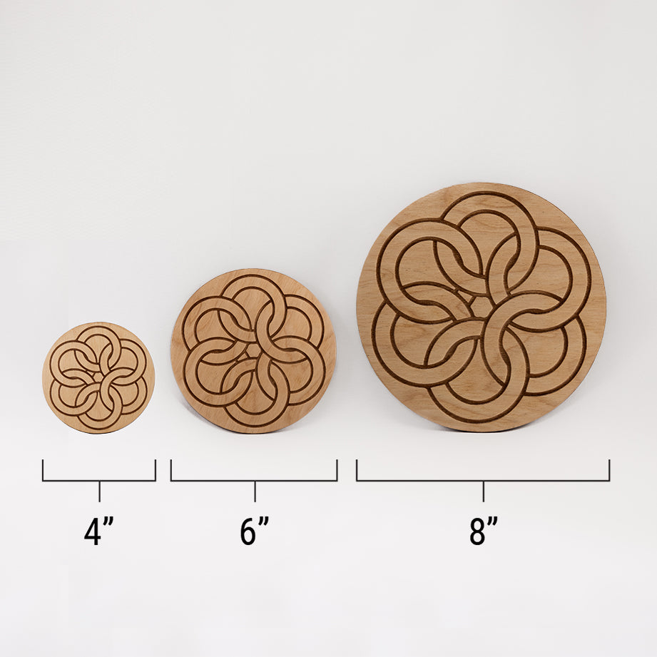 Three different sizes of the circular wooden laser-cut crystal grid engraved with a Celtic ring knot against a white background with a ruler underneath all three. The smallest measuring 4", the middle 6", and the largest 8".