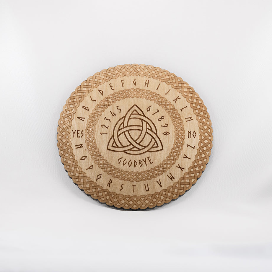 Circular Baltic birch laser-cut spirit  board engraved with the words "yes", "no", "goodbye", as well as the entire alphabet. The board has the Celtic Triquetra symbol in the centre and a decorative die-cut braid border.