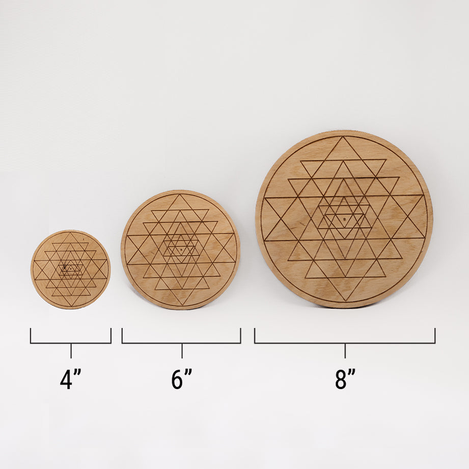 Three different sizes of the circular wooden laser-cut crystal grid engraved with Sri Yantra. against a white background with a ruler underneath all three. The smallest measuring 4", the middle 6", and the largest 8".