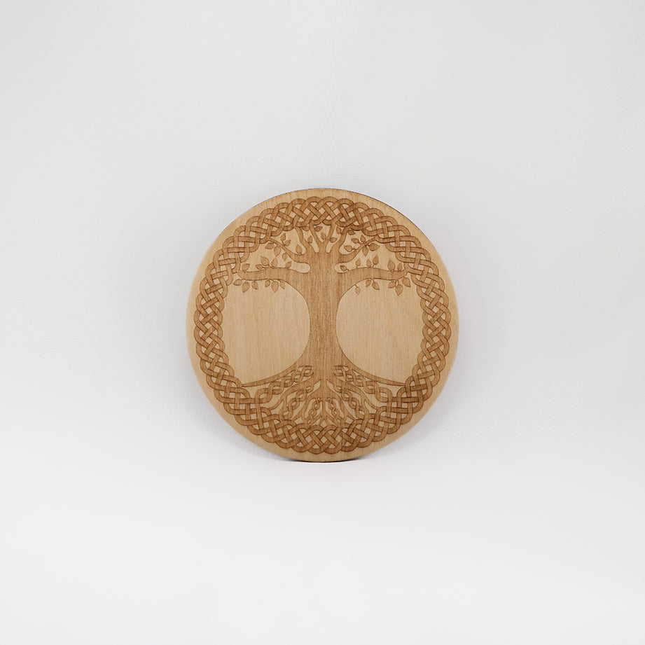 A circular wooden laser-cut crystal grid engraved with the Celtic Tree of Life. with a plain white background. 