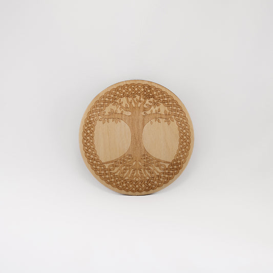 A circular wooden laser-cut crystal grid engraved with the Celtic Tree of Life. with a plain white background.