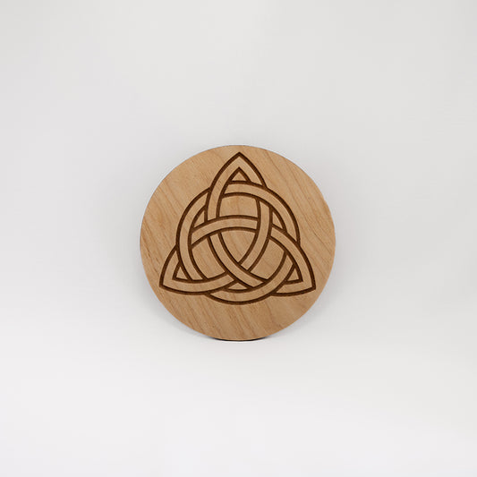 A circular wooden laser-cut crystal grid engraved with the Celtic Triquetra symbol with a plain white background. 