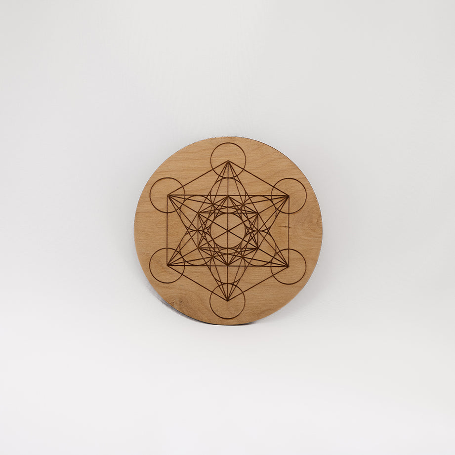 A circular wooden laser-cut crystal grid engraved with Metatron's Cube with a plain white background. 