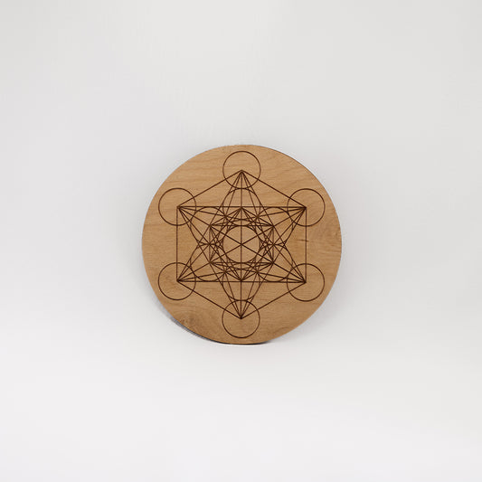 A circular wooden laser-cut crystal grid engraved with Metatron's Cube with a plain white background.